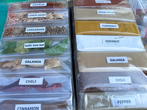 Stock photo showing a close-up, elevated view of prepackaged cellophane bags of dried and powdered herbs and spices being sold by from a street market display.