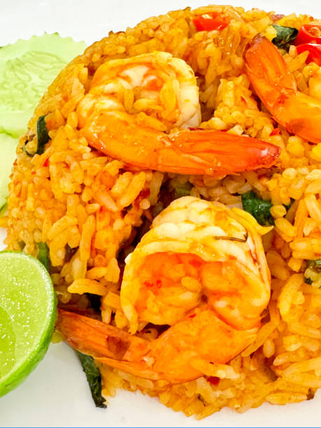 istock Full frame image of white plate containing Thai prawn fried rice (Khao Pad Goong), jasmine rice, shrimp with tails, onion, Chinese broccoli leaf, chopped red chilli in fish sauce (prik nam pla) served with lime wedges, elevated view 2070395762