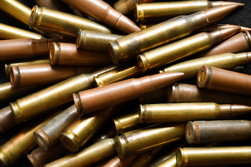 Old or unused sniper bullets on wooden plank, soft focus.