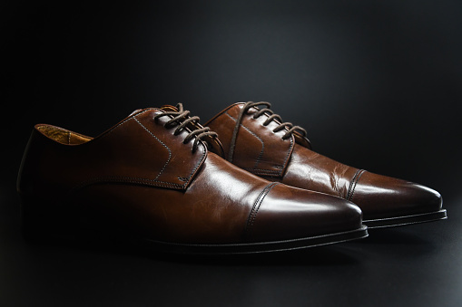 Photo of dark brown fancy shoes on black studio background