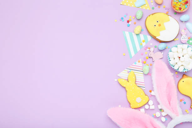 istock Easter gingerbread cookies with paper flags, rabbit ears, marshmallows and sprinkles on purple background 2070528710