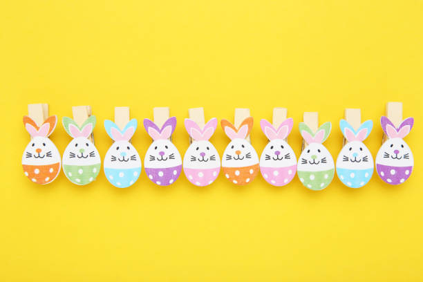 istock Easter concept. Clothespins with eggs and rabbit faces on yellow background 2070532859