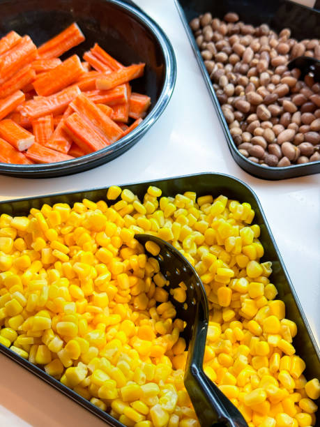 close-up image of hotel self service refrigerated buffet display, salad bar trays of sweetcorn, carrot batons and haricot bean, ingredients for self made salad, serving spoon, salad vegetable restaurant buffet - focus on foreground eating utensil serving utensil tray imagens e fotografias de stock