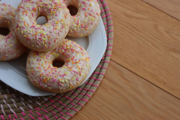 istock Donuts with white glaze and pastel sprinkles on a white plate on table 2070549453