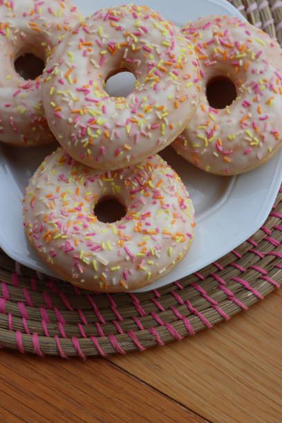 istock Donuts with white glaze and pastel sprinkles on a white plate on table 2070549968