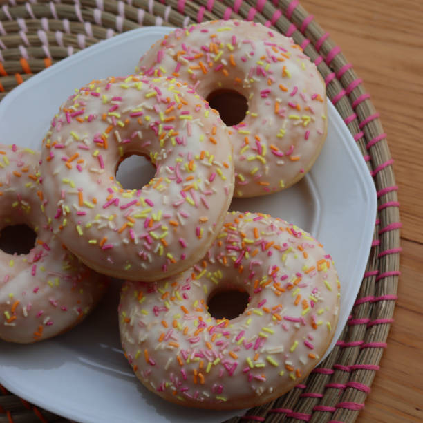 istock Donuts with white glaze and pastel sprinkles on a white plate on table 2070550487