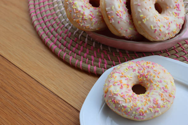 istock Donuts with white glaze and pastel sprinkles in a pink bowl on table 2070551003