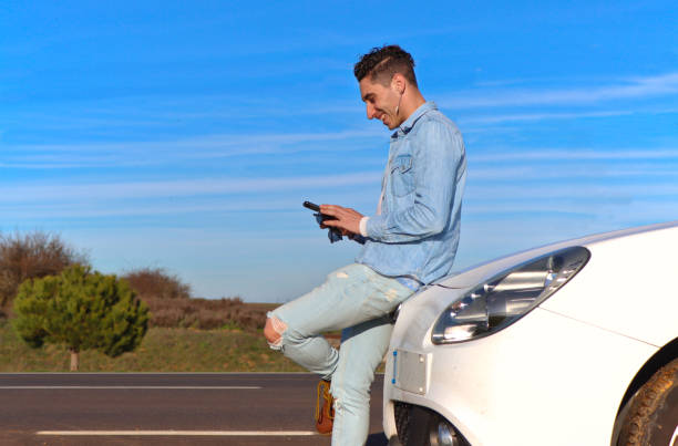 Curly haired Caucasian man leaning on his car