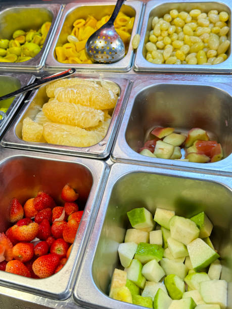 полнокадровое изображение холодильного буфета с самообслуживанием в отеле, фруктовый салат-бар, металлические подносы с очищенными и наре - refrigerator healthy eating mango fruit стоковые фото и изображения