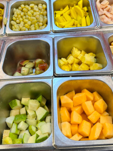 полнокадровое изображение холодильного буфета самообслуживания отеля, фруктовый салат-бар, металлические подносы с очищенными и нарезанн - refrigerator healthy eating mango fruit стоковые фото и изображения
