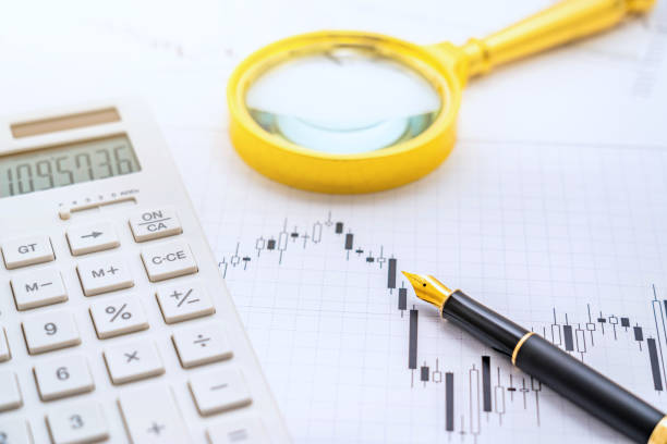 istock Calculator, magnifying glass, and pen placed on the candlestick chart 2070582079