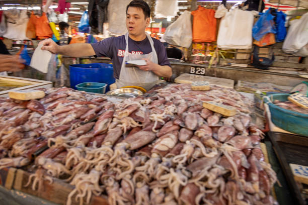 Chow Kit market, Kuala Lumpur, Malaysia - January 10th 2024: Male fishmonger selling octopuses at a stall in the famous food market in the center of the capital