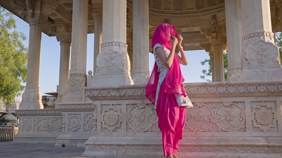 Indian young woman inside a temple, Jaipur. Jaipur is known as the Pink City, because of the color of the stone exclusively used for the construction of all the structures.