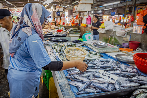 Chow Kit market, Kuala Lumpur, Malaysia - January 10th 2024:  Female customer checking the fresh fish at a fishmongers stall in the famous food market in the center of the capital