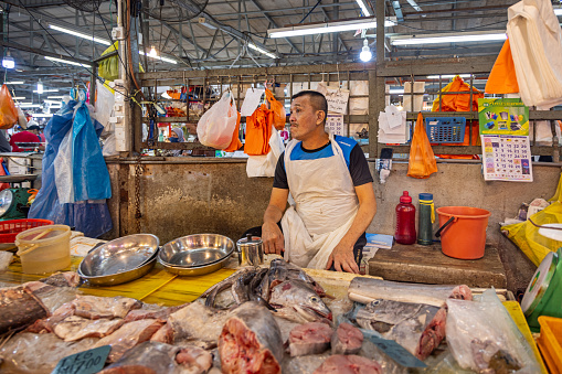 Chow Kit market, Kuala Lumpur, Malaysia - January 10th 2024:  Male fishmonger having a quiet moment at a stall in the famous food market in the center of the capital