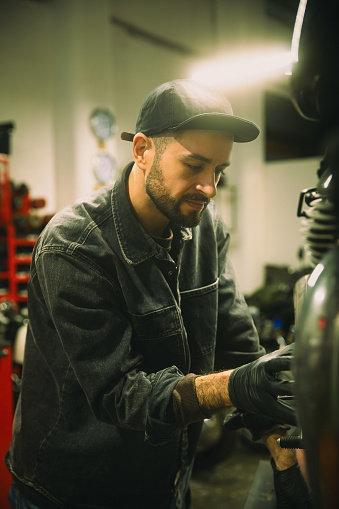 Mechanic in auto repair shop is customizing motorcycle engine