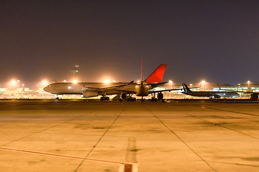Grounded aircraft at night with airport terminal in background.