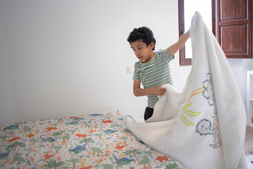 Child making bed at home