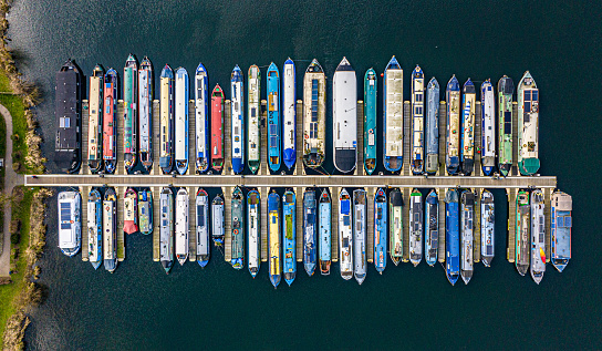 Aerial photo from a drone of a row of canal boats moored along a jetty.