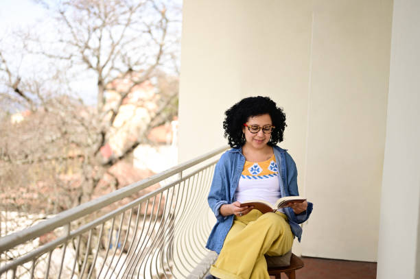 istock Cheerful female reading book at outdoors patio. 2070700750