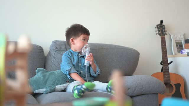 Boy using inhalation nebulizer with toys in foreground