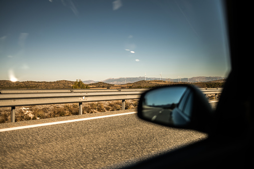 First person view of driving a car on a highway in south of Spain on a sunny day. Shot of rear view window and the view.