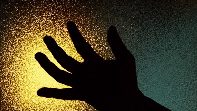 Shadow of a zombie hand, behind frosted glass