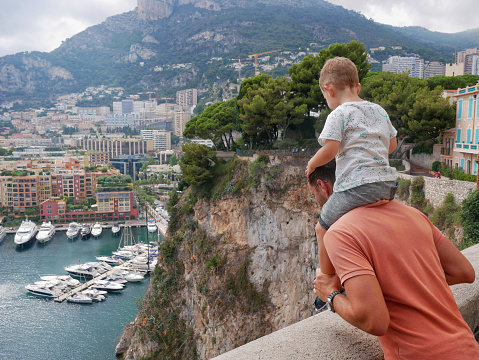 A man with a child are looking at the panoramic view of the port in Monte Carlo, Monaco.