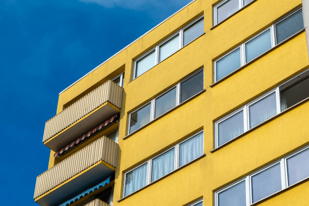 yellow building with a balcony and many windows the building is tall and has a modern look