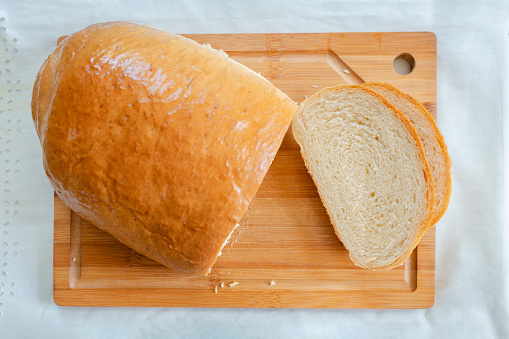 Freshly baked homemade bread resting on a table, delicately sliced and awaiting to be savored