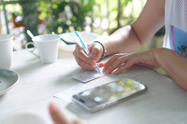 istock Business woman checking documents or note working for home with smartphone on table or reminder planner note in bill payment 2070800301