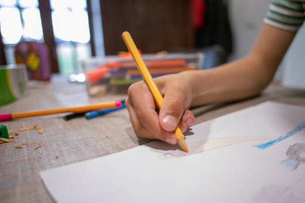 Little Asian boy holding colored pencils and drawing in Chinese restaurant after eating dinner