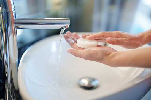 Cropped shot of a woman is seen maintaining hand hygiene by washing her hands with soap in the sink. This image emphasizes the importance of proper handwashing to prevent the spread of germs and maintain personal hygiene.