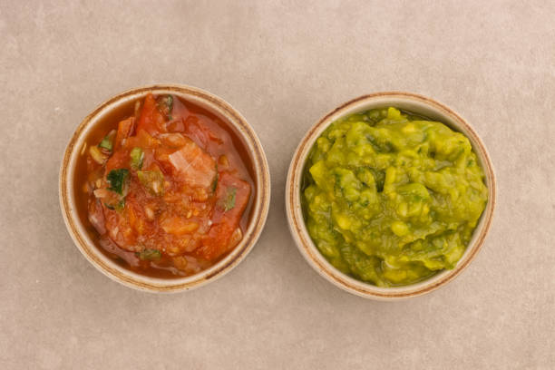 Tortilla chip dipped in salsa with bowl in background with copy space.