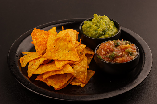 Tortilla Chips or Nachos with Two Super Bowl Dips which are Salsa and Guacamole.