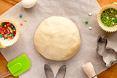 Dough for making Easter cookies, cookie cutters, sugar sprinkles. Festive Easter background for baking.