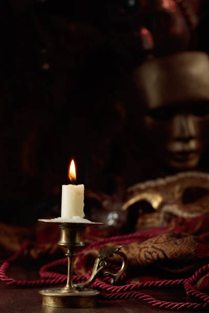 istock Burning candle in an old brass candlestick and carnival masks. 2070869266