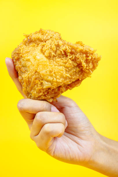 istock Female hand holding fried chicken on yellow background. 2070895198