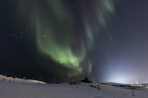 Aurora borealis (Northern Lights) on cloudy sky.\nHammerfest - Norway.
