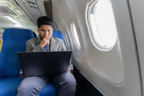 istock Young professional Asian man working with laptop computer and smartphone while sitting in airplane in airplane cabin during business and leisure travel. 2070918315