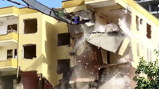 Renovation of Housing Stock, Concept of Rebirth and Improvement of Living Conditions, Excavator with Hydraulic Claw Breaks Down Old Multi-storey Residential Building, Water Pressure Knocks Down Dust.