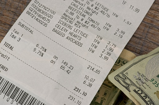 Grocery receipt with cash on a wood background