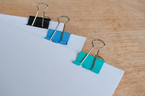 Blank document papers with colored paper clips pastel on wooden table. Document management concept.