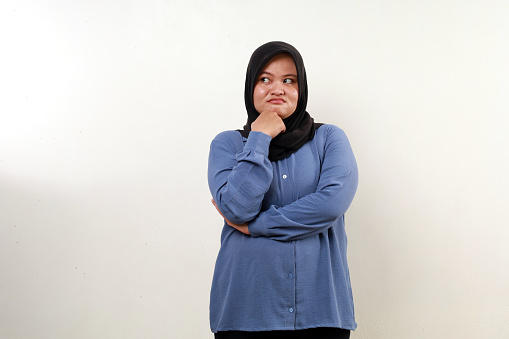 Disappointed asian muslim woman standing while looking sideways