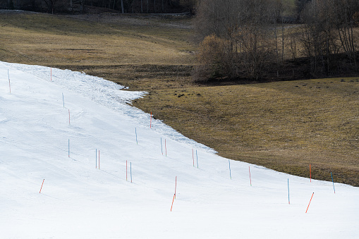 slalom poles on fake snow ski slope on mountain meadow during too warm winter season as impact of global warming
