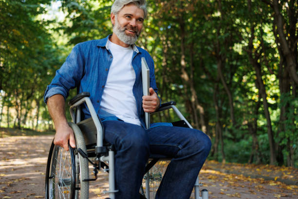 istock Accessible Work Environments: Man in Wheelchair with Laptop in Park 2070998853