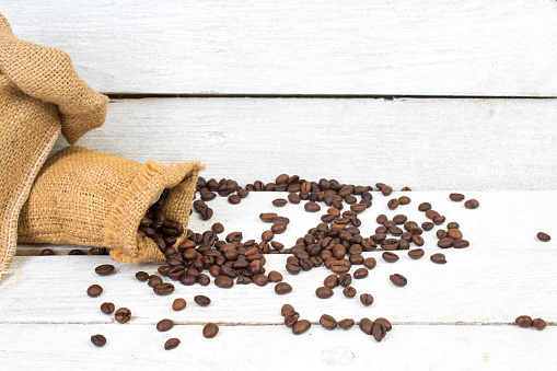 Sack with brown roasted coffee beans. Burlap sack. Scoop with grains