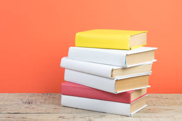 istock Books stacking. Books on wooden table and orange background. Back to school. Copy space for ad text. 2071063174