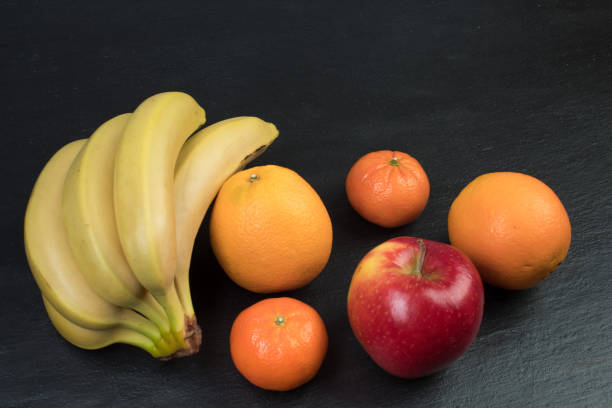 Fruits. Bananas, apples, oranges tangerines on a black background