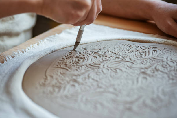 istock Potter is cutting out shape of plate from the clay 2071076771